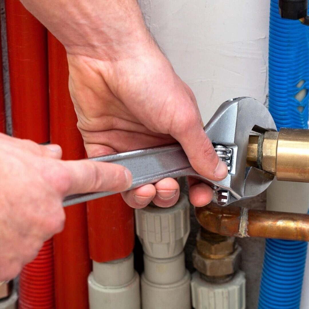 A plumber is fixing a broken pipe with a wrench to ensure proper water supply.